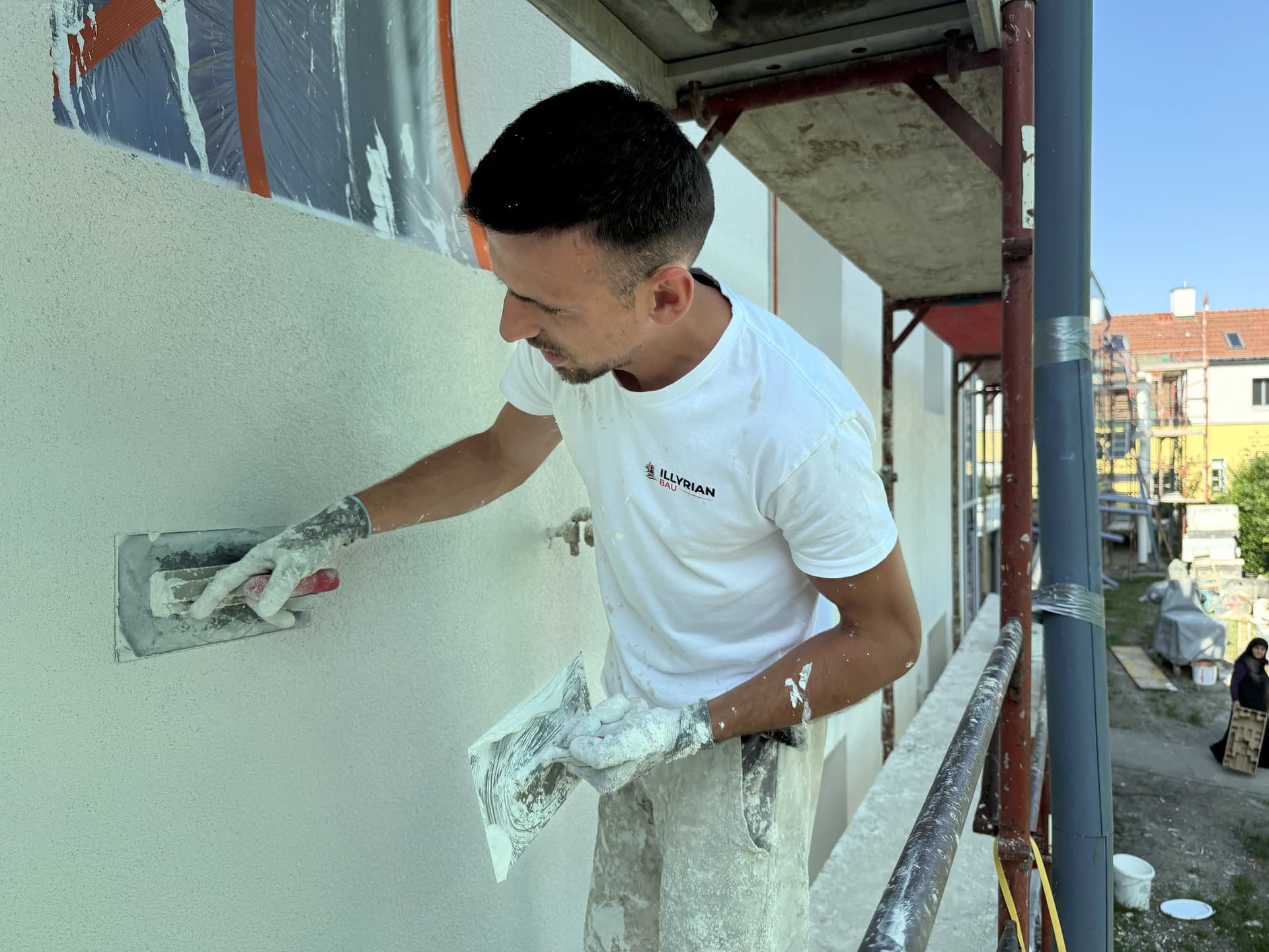 Arbeiter glättet Fassade während einer Sanierung